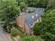 View of the brick townhome with well-maintained landscaping and mature trees at 3100 Coachmans Way, Durham, NC 27705