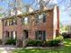 Charming brick townhome featuring dormer windows, dark shutters, and a well-manicured front yard at 3100 Coachmans Way, Durham, NC 27705