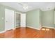 Bedroom with hardwood floors, green walls, a ceiling fan, and a door to a hallway at 3109 E Folkestone Pl, Raleigh, NC 27604
