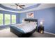 Spacious bedroom with a tray ceiling, blue walls, and three windows at 3219 Ranbir Dr, Durham, NC 27713