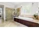 Elegant bathroom featuring a glass-enclosed shower and a luxurious soaking tub with travertine surround at 3513 Forest Oaks Dr, Chapel Hill, NC 27514