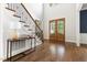 Bright foyer with hardwood floors, a staircase with iron railings, and a view of the double front doors at 3513 Forest Oaks Dr, Chapel Hill, NC 27514