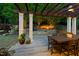 Scenic outdoor dining area with a wooden table and chairs, overlooking a charming stone patio and fire pit at 3513 Forest Oaks Dr, Chapel Hill, NC 27514