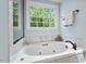 Relaxing bathroom with a soaking tub, marble surround, and large window views at 3826 Regent Rd, Durham, NC 27707