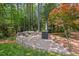Paver patio with outdoor seating and a stone fire pit surrounded by mature trees at 3826 Regent Rd, Durham, NC 27707