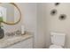 Cozy half bathroom with granite countertops, round mirror and decorative wall art above the toilet at 406 Sapphire Dr, Durham, NC 27703
