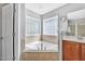 Corner soaking tub surrounded by tile and corner windows at 421 Gooseberry Dr, Holly Springs, NC 27540