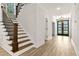 Inviting entryway with dark wood staircase, wood floors, and view of the front door and foyer at 45 Hamilton Way, Youngsville, NC 27596
