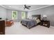 Spacious bedroom with a ceiling fan, carpeted floors, and natural light from two windows at 4513 Touchstone Forest Rd, Raleigh, NC 27612
