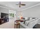 Spacious living room with plush carpeting, a ceiling fan, a large sectional, and an open view to the sunroom at 4513 Touchstone Forest Rd, Raleigh, NC 27612
