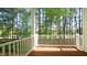 Inviting covered porch with wooden flooring and white railing overlooking a lush wooded area at 4517 Pale Moss Dr, Raleigh, NC 27606