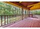 Covered back porch with a wood railing and natural scenery beyond the back of the house at 5204 William And Mary, Raleigh, NC 27616