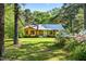 Inviting wood-sided home with a well-maintained lawn and blooming flowers, framed by mature trees at 5204 William And Mary, Raleigh, NC 27616