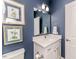 Stylish powder room featuring blue walls, framed artwork, and a vanity with a white countertop and cabinet at 524 Auguston Ct, Sanford, NC 27330