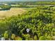 Aerial view showcasing lush trees surrounding the home and picturesque open fields at 580 Greenbriar Farm Trl, Siler City, NC 27344