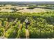 Aerial view showcasing lush trees surrounding the home and picturesque open fields at 580 Greenbriar Farm Trl, Siler City, NC 27344