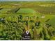Aerial view showcasing lush trees surrounding the home and picturesque open fields at 580 Greenbriar Farm Trl, Siler City, NC 27344
