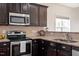 Close-up of kitchen with stainless steel appliances, dark cabinets, and granite countertops at 632 Hunters Ridge Dr, Fuquay Varina, NC 27526