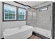 Bright bathroom featuring a freestanding tub under windows and a separate glass-enclosed shower with marble tiling at 66 Privette Way, Zebulon, NC 27597