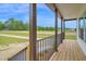 Covered porch with wooden decking, stairs, black metal railing, and nature views at 66 Privette Way, Zebulon, NC 27597