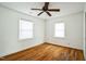 Cozy bedroom with hardwood floors, white walls, two windows, and ceiling fan at 704 N King Charles Rd, Raleigh, NC 27610