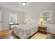 This bedroom features two windows for natural light, hardwood floors, lamps, and a comfortable floral bed at 705 N Gurney St, Burlington, NC 27215