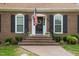 Inviting front entrance with brick steps, an American flag, and black shutters under a clear sky at 705 N Gurney St, Burlington, NC 27215