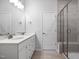 Bright bathroom featuring double sinks, white cabinets, quartz countertops, and a walk-in shower with glass door at 728 Ben Ledi Ct, Raleigh, NC 27603
