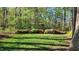 Lush backyard with vibrant azaleas, a charming wooden arbor, and mature trees creating a serene outdoor oasis at 85 Rivers Edge Ct, Timberlake, NC 27583