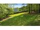 Large backyard featuring lush green grass and tree coverage with a wooden fence outlining the perimeter of the property at 9016 New Century Rd, Wake Forest, NC 27587