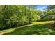 Backyard view with grassy lawn, mature trees, and partial view of the house behind a wooden fence at 9016 New Century Rd, Wake Forest, NC 27587