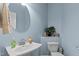 Powder bathroom with blue walls, white toilet, a decorative shelf, and oval mirror above a white sink basin at 9016 New Century Rd, Wake Forest, NC 27587