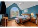 A serene bedroom with blue walls, a large arched window, and hardwood floors creates a cozy and inviting space at 9016 New Century Rd, Wake Forest, NC 27587