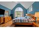 Bedroom with blue walls, hardwood floors, and a large window, providing a bright and airy atmosphere at 9016 New Century Rd, Wake Forest, NC 27587