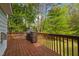 Wooden deck with a grill and storage cabinet, overlooking a green backyard with tall trees at 9016 New Century Rd, Wake Forest, NC 27587