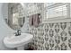 A stylish powder room features unique leaf wallpaper, enhancing the charming and modern design at 9212 Linslade Way, Wake Forest, NC 27587