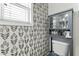A bathroom shows a toilet with a gray cabinet above it, complemented by leaf-patterned wallpaper at 9212 Linslade Way, Wake Forest, NC 27587