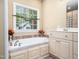 Bright bathroom featuring a soaking tub beneath a window with a view of the outdoors and a tile surround at 936 Elbridge Dr, Raleigh, NC 27603