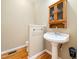Cozy half bath with pedestal sink, cabinet and wood flooring at 936 Elbridge Dr, Raleigh, NC 27603