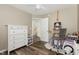 Neutral bedroom with a white dresser, wood-look floors, and an easel for art projects at 101 Rustic Pine Ct, Apex, NC 27502