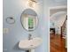 Charming powder room with a pedestal sink, round mirror, and stylish fixtures, offering a fresh feel at 101 Rustic Pine Ct, Apex, NC 27502
