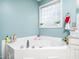 Bright bathroom featuring a corner soaking tub with glass block window and tiled surround at 104 Hamby Ct, Garner, NC 27529
