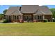 Expansive backyard of a brick home featuring a well-maintained lawn and a covered patio with lovely detailing at 121 Westchase Run, Sanford, NC 27330