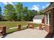 Beautiful backyard featuring a stone patio with brick columns, a lush green lawn, and a detached garage at 121 Westchase Run, Sanford, NC 27330