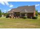 Gorgeous brick home featuring a spacious backyard with lush greenery and a charming covered patio area at 121 Westchase Run, Sanford, NC 27330