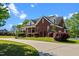 Brick home with well-kept landscaping, a large driveway, and mature trees surrounding the property at 121 Westchase Run, Sanford, NC 27330