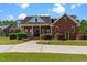 Stately brick home featuring a covered front porch, manicured landscaping, and a spacious driveway at 121 Westchase Run, Sanford, NC 27330