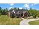 An angled view of a brick house showing lush landscaping and a curved driveway leading up to the front at 121 Westchase Run, Sanford, NC 27330