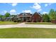 A brick home with a well-manicured front yard, elegant porch, and curved driveway leading to the entrance at 121 Westchase Run, Sanford, NC 27330