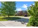 Brick home with a curved driveway and lush landscaping, set against a backdrop of mature trees and blue sky at 121 Westchase Run, Sanford, NC 27330